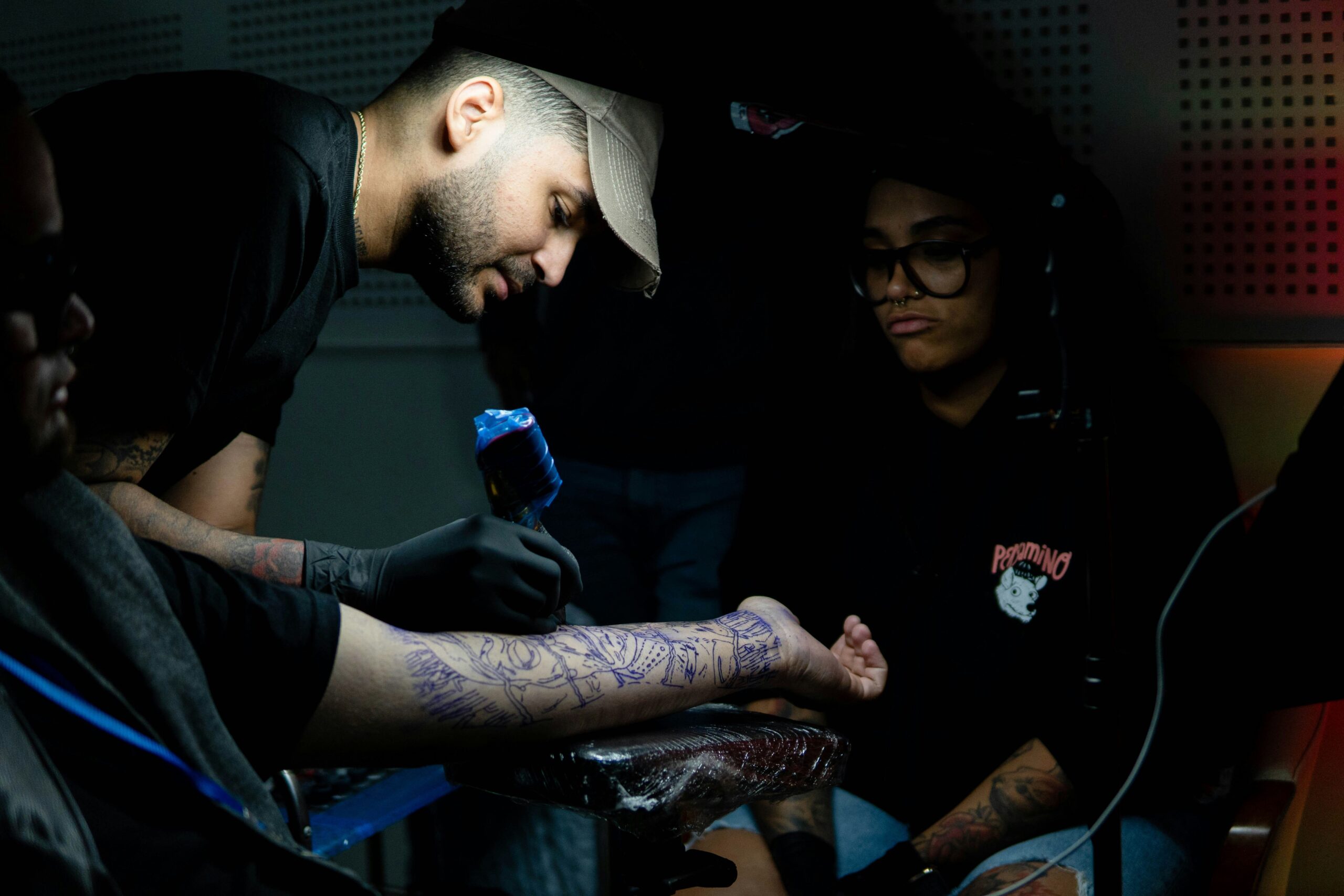 persona tatuando, mientras otra aprende