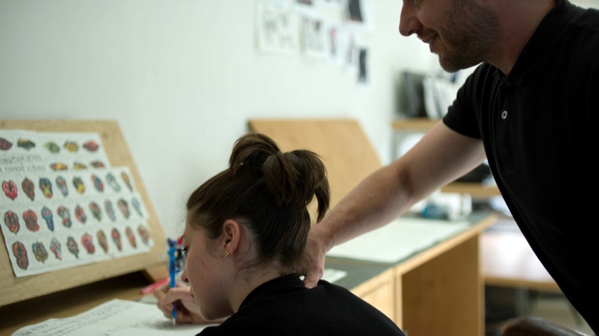 Correccion postural de una alumna al hablar de ergonomia del tatuador en la escuela